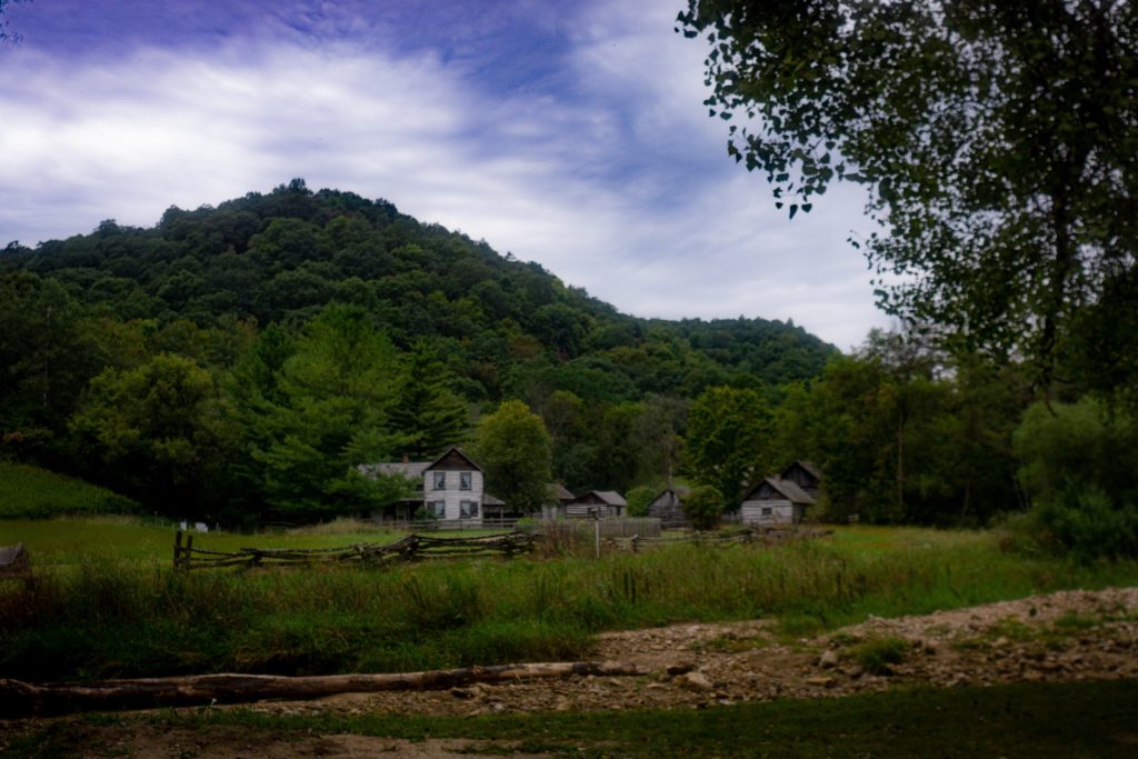 A mountain with a homey looking building in front of it, with a wooden gate