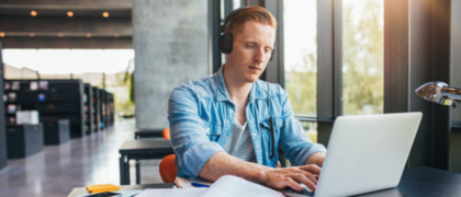 Man wearing headphones while using a laptop studying online.